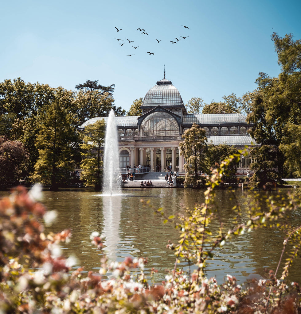 Palacio de cristal en el parque del retiro con lago, fuentes y flores en Madrid
